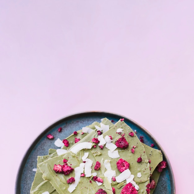 Tablette De Chocolat Vert Avec Des Framboises Séchées Sur Une Plaque Sur Fond Violet