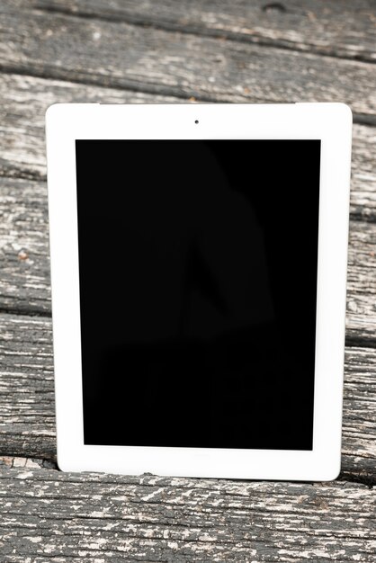 Tablette numérique réaliste avec un écran blanc sur une planche texturée en bois