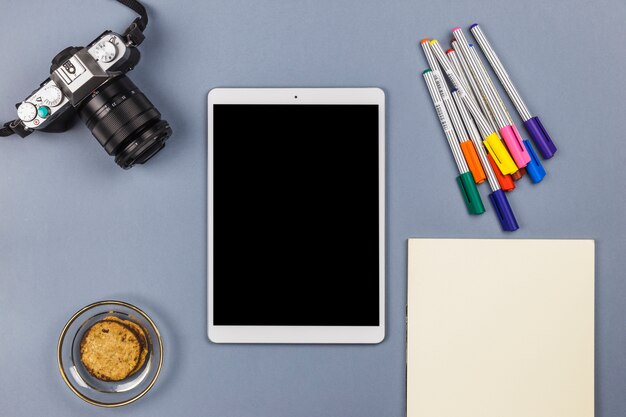 Tablette près de la caméra, papier, biscuits dans un bol et feutres