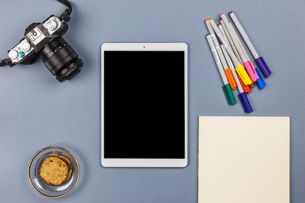 Tablette près de la caméra, papier, biscuits dans un bol et feutres