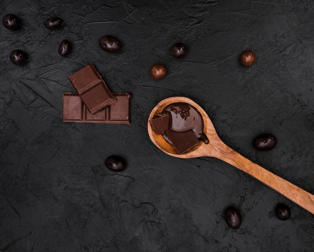Photo gratuite tablettes de chocolat et cuillère en bois avec sirop de chocolat