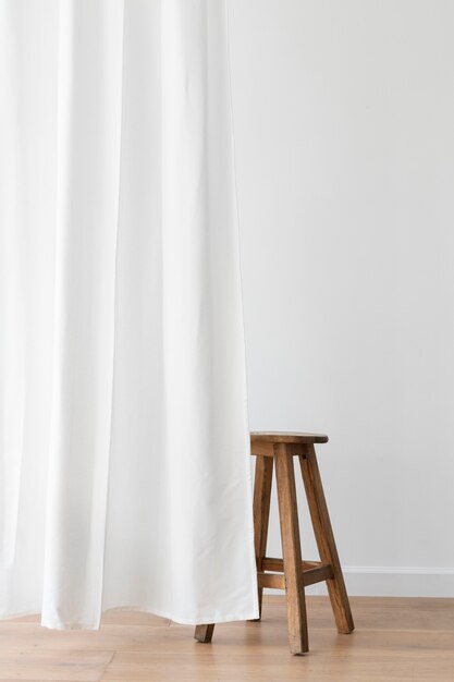 Tabouret en bois derrière un rideau blanc