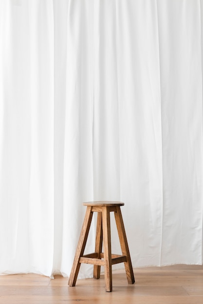Photo gratuite tabouret en bois devant un rideau blanc