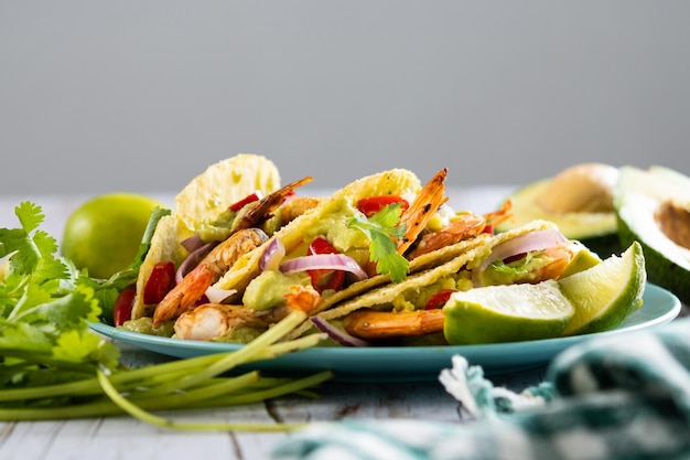 Tacos mexicains aux crevettes guacamole et légumes sur table en bois