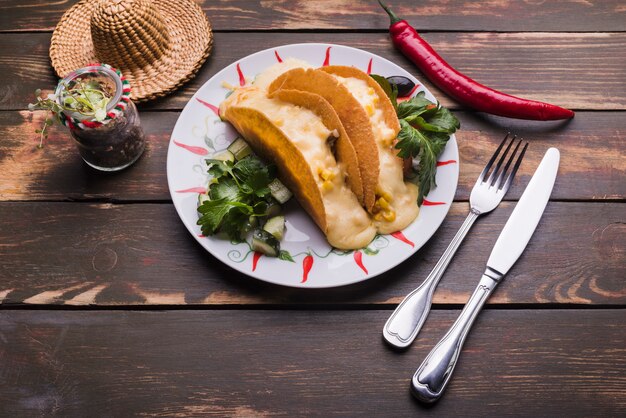 Tacos parmi les légumes sur le plat près de chili et sombrero