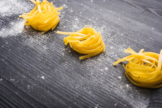 Tagliatelles crues saupoudrées de farine blanche sur fond en bois