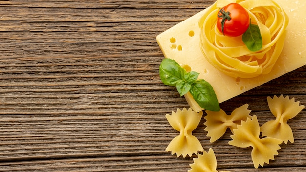 Photo gratuite tagliatelles farfalle non cuites avec feuilles de basilic, tomates à pâte dure et espace de copie