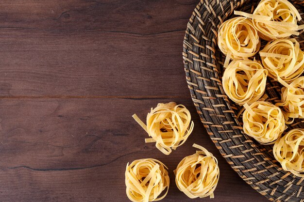 Tagliatelles pâtes en vue de dessus de panier avec copie espace sur une surface en bois