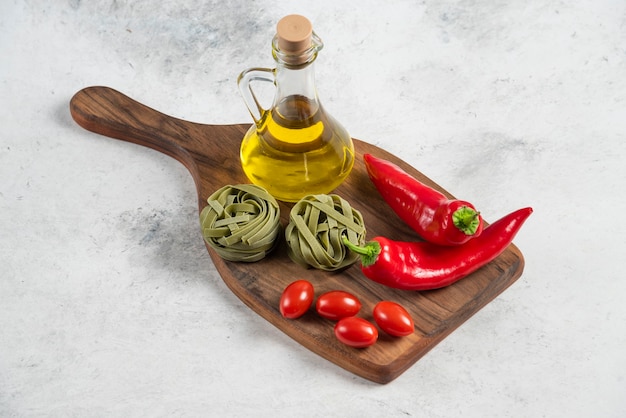 Tagliatelles vertes, légumes et huile d'olive sur planche de bois.