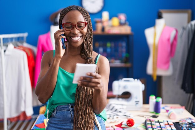 Tailleur de femme afro-américaine parlant sur un cahier de lecture de smartphone à l'atelier