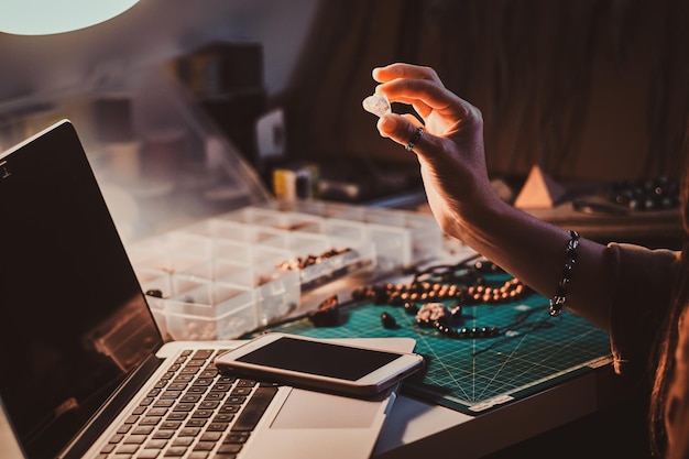 Le talentueux fabricant de perles de bijoux tient à la main une pierre semi-précieuse cristalline.