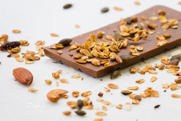 Étaler les fruits secs sur la barre de chocolat sur un fond blanc