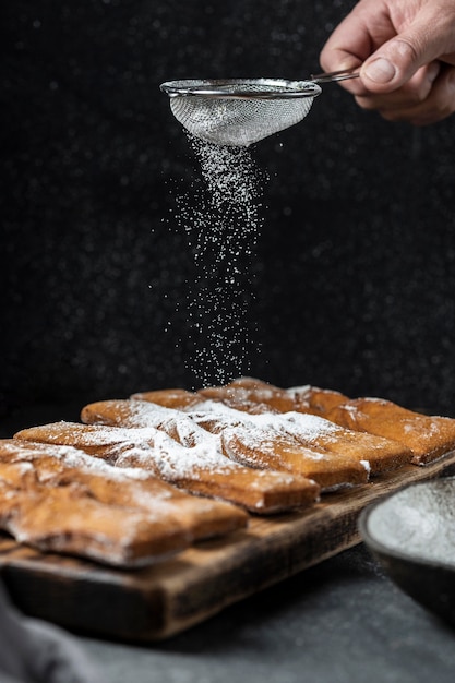 Tamiser à la main le sucre en poudre sur les desserts