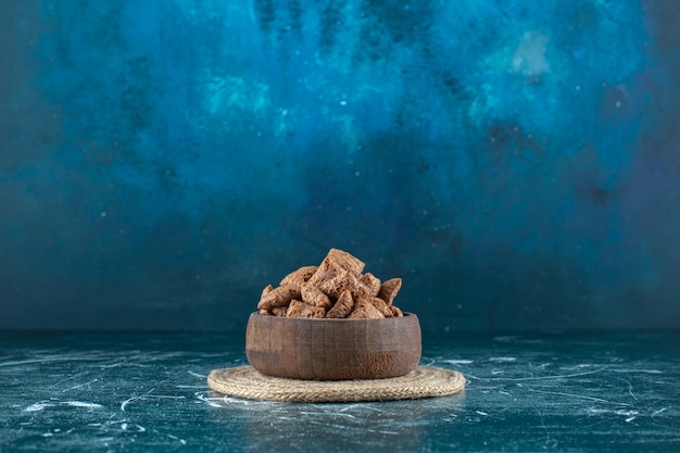 Tampons de maïs au chocolat dans un bol sur un dessous de plat, , sur fond bleu. photo de haute qualité