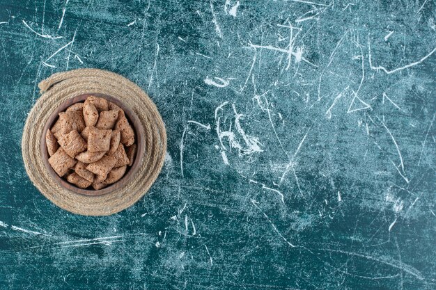 Tampons de maïs au chocolat dans un bol sur un dessous de plat, , sur la table bleue.