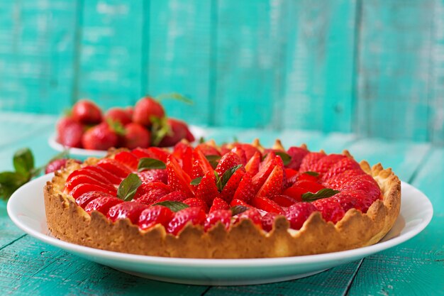 Tarte aux fraises et chantilly décorée de feuilles de menthe.