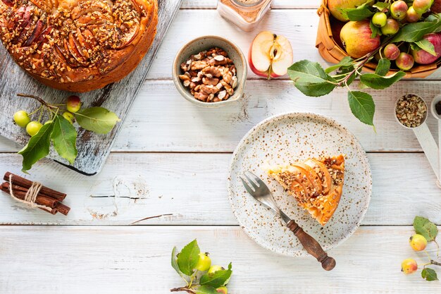 Tarte aux pommes maison et ingrédients sur un fond en bois blanc. Vue de dessus.