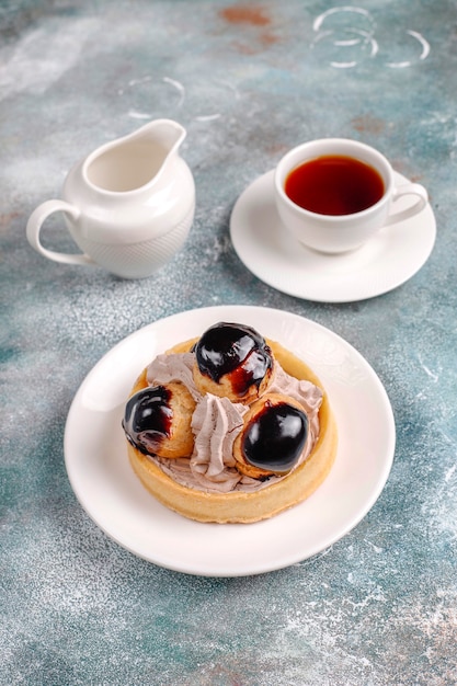 Tarte aux profiteroles sur le dessus avec de la crème fouettée.