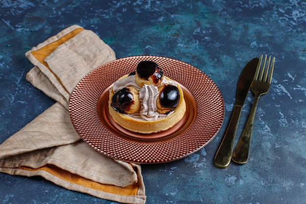 Tarte aux profiteroles sur le dessus avec de la crème fouettée.