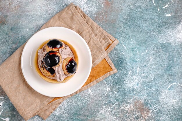 Tarte aux profiteroles sur le dessus avec de la crème fouettée.