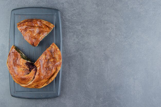 Tarte farcie aux verts sur une planche à découper noire.