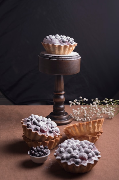 Tarte maison aux baies et crème fouettée sur un bureau marron sur fond noir