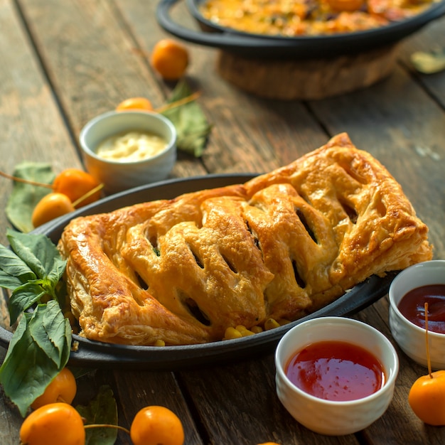 Tarte à la viande vue de face avec sauces et néflier