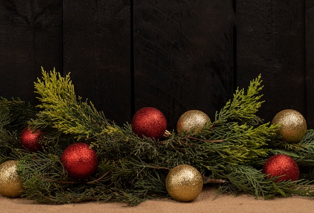 Un tas de branches de chêne et de boules brillantes sur un fond en bois noir