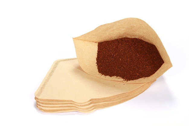 Tas de café fraîchement moulu dans un filtre isolé sur fond blanc