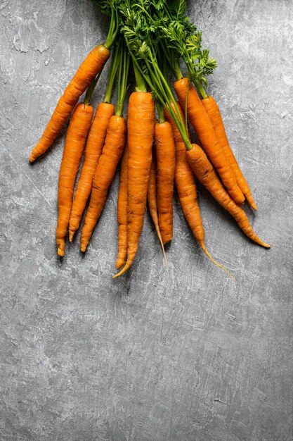 Tas de carottes biologiques fraîches sur une vue aérienne de dessus de cuisine gris