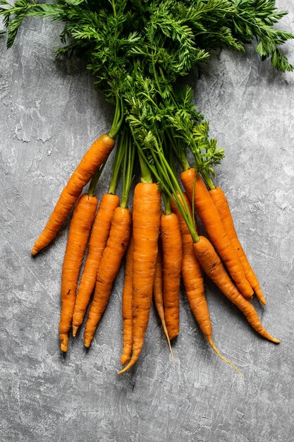 Tas de carottes biologiques fraîches sur une vue aérienne de dessus de cuisine gris