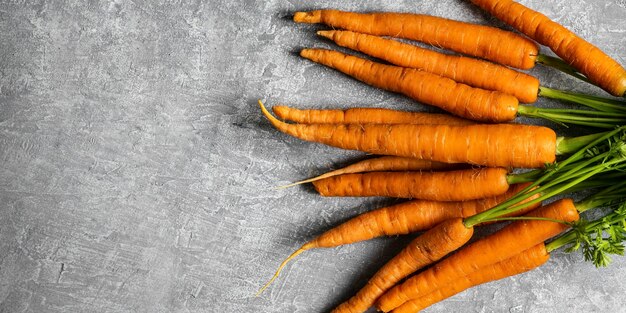 Tas de carottes biologiques fraîches sur une vue aérienne de dessus de cuisine gris