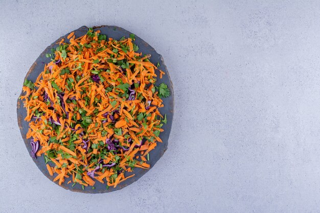 Tas de carottes et de chou rouge haché en salade sur une planche sur fond de marbre. photo de haute qualité