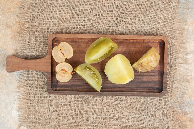 Tas de cornichons mixtes sur planche de bois.