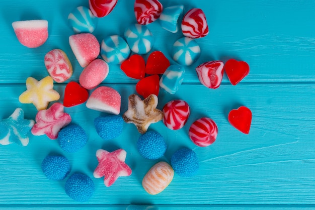 Un tas de délicieux bonbons à la gelée en forme d'étoiles, de coeurs et de cercles sur une table en bois