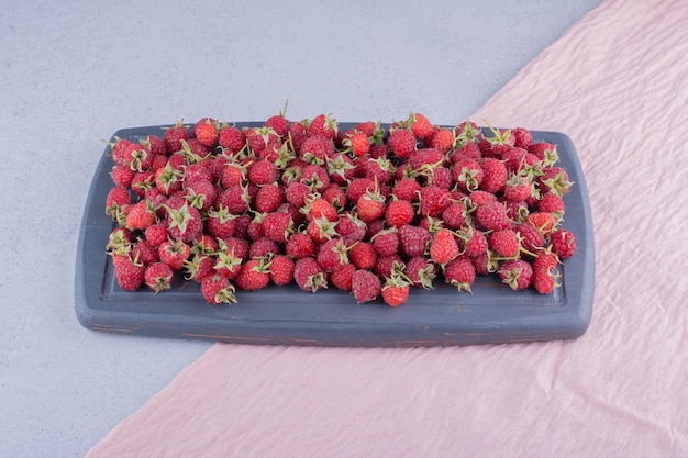 Tas de framboises sur une planche marine sur fond de marbre. photo de haute qualité