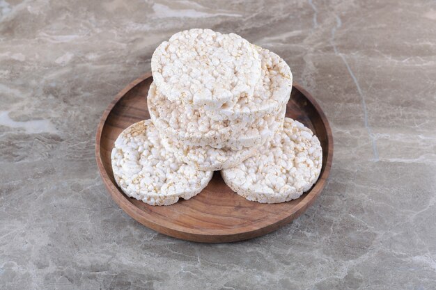 Un tas de gâteaux de riz soufflé sur le plateau en bois, sur le fond de marbre.