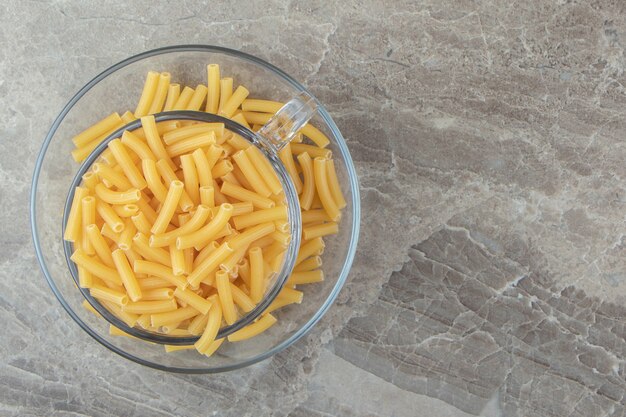 Tas de macaronis crus dans une tasse en verre.