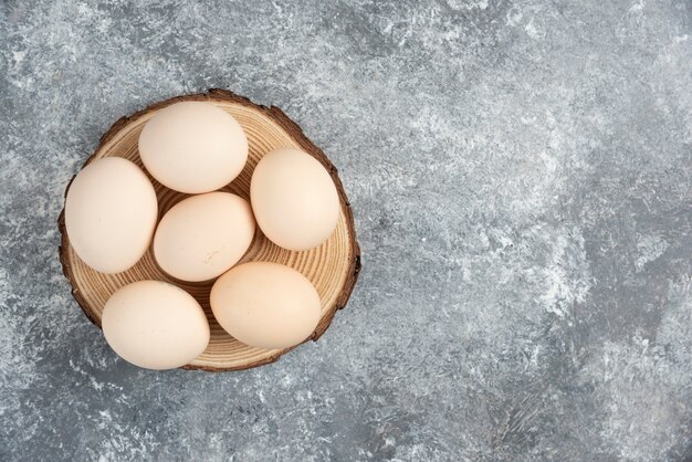 Tas d'oeufs crus frais biologiques placés sur un morceau de bois.