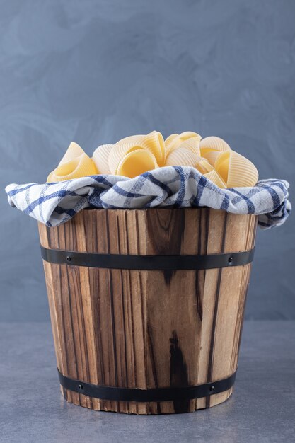 Tas de pâtes de coquille crue dans un seau en bois.