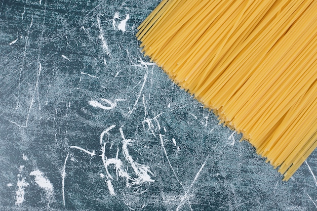Tas de pâtes non préparées de spaghettis de grains entiers attachés avec une corde sur fond de marbre