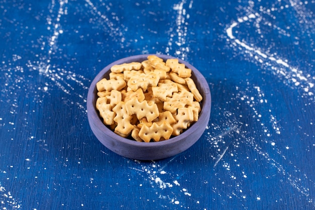 Tas de petits craquelins salés placés dans un bol bleu