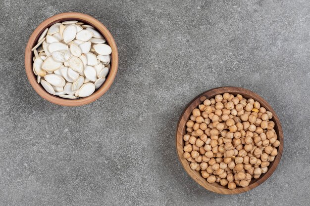 Tas de pois jaunes et de graines de citrouille dans des bols en bois.