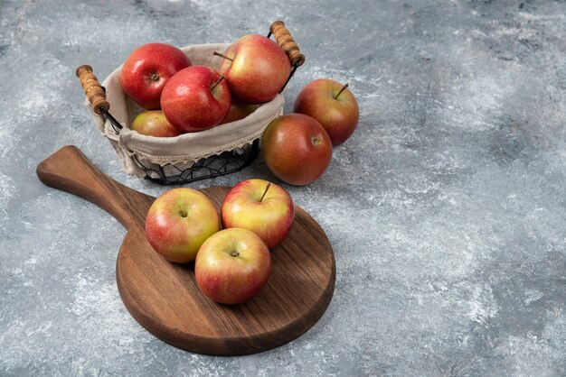 Tas de pommes mûres fraîches sur planche de bois et dans le panier.