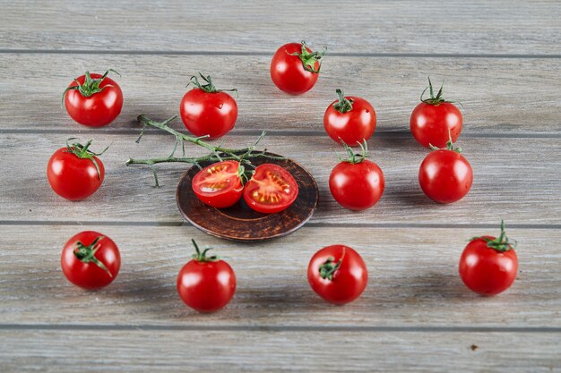 Tas de tomates fraîches juteuses et de tranches de tomate sur table en bois.