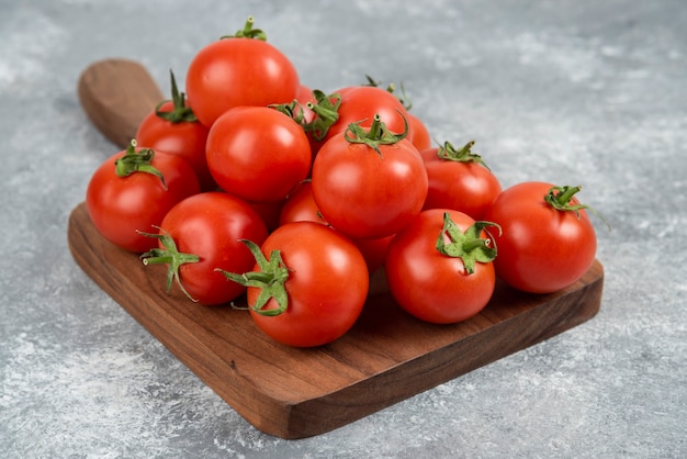 Tas de tomates fraîches rouges sur une planche à découper en bois.