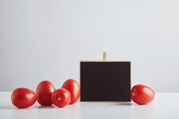 Tas de tomates rouges fraîches de ferme biologique avec étiquette de prix de tableau de craie isolé sur tableau blanc, prêt à vendre.