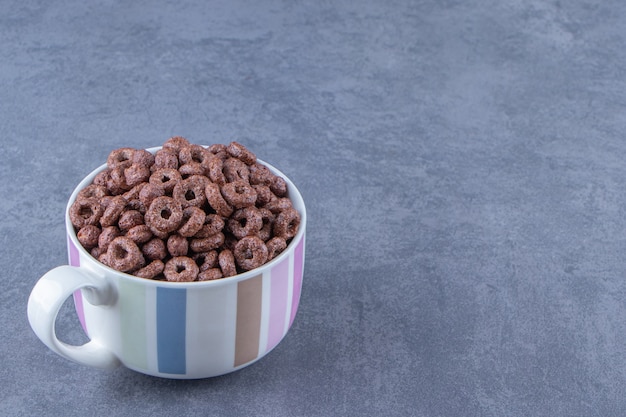 Photo gratuite une tasse d'anneaux de maïs , sur le fond bleu.