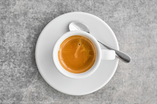 Tasse blanche avec café expresso fort parfumé avec mousse épaisse dans un café grec traditionnel Vue de dessus du café avec soucoupe sur une table en marbre gris idée de fond ou d'affiche