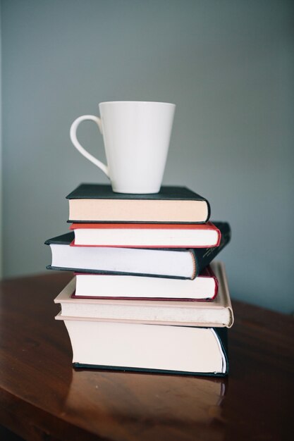 Tasse blanche sur une pile de livres